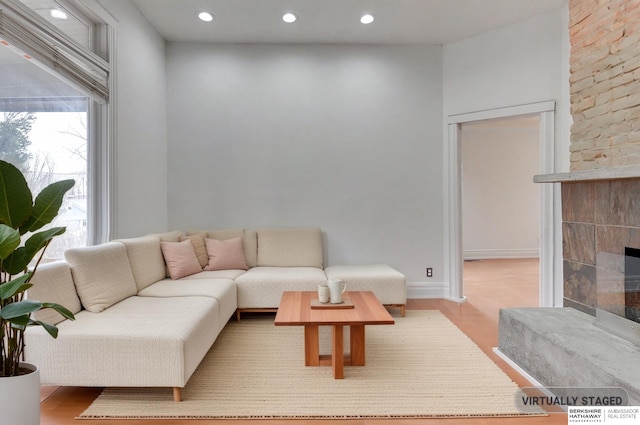 living area featuring a tiled fireplace, wood finished floors, and recessed lighting