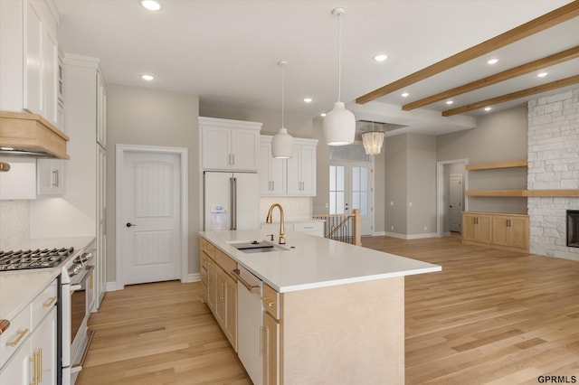kitchen with a center island with sink, a sink, light wood finished floors, and white appliances