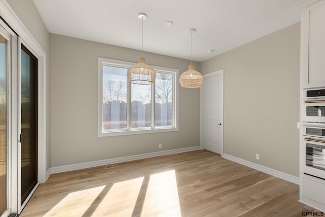 unfurnished dining area with baseboards and light wood-style floors