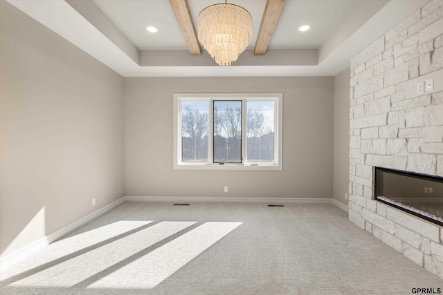 unfurnished living room with baseboards, an inviting chandelier, beamed ceiling, and a stone fireplace