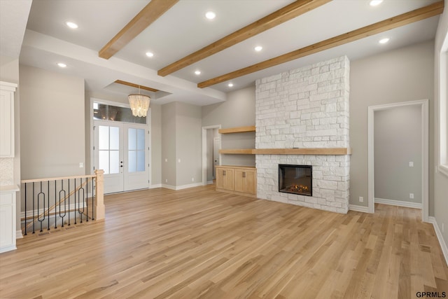 unfurnished living room with beamed ceiling, light wood-type flooring, baseboards, and french doors