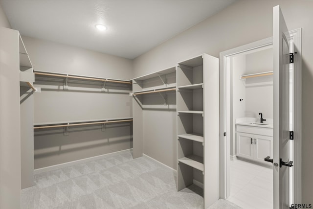 walk in closet featuring a sink and light colored carpet