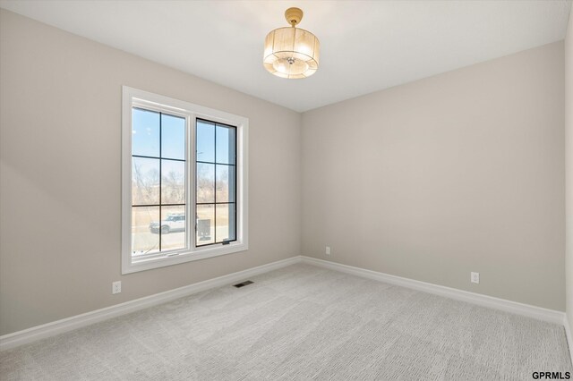 empty room with light colored carpet, visible vents, and baseboards