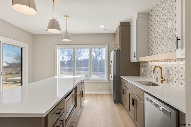 kitchen featuring light countertops, a sink, tasteful backsplash, a center island, and stainless steel appliances