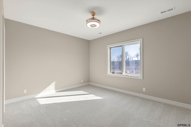 empty room featuring baseboards, visible vents, and light carpet
