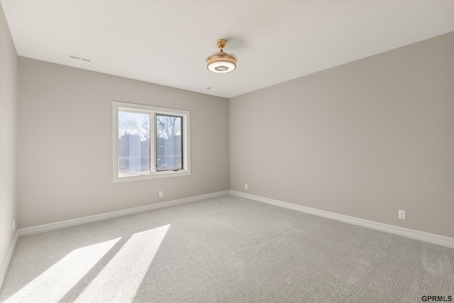 spare room with baseboards, visible vents, and light carpet