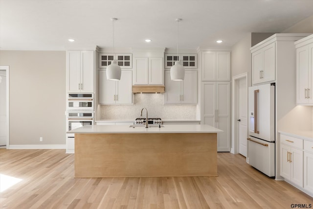 kitchen with light countertops, light wood finished floors, white appliances, a kitchen island with sink, and tasteful backsplash