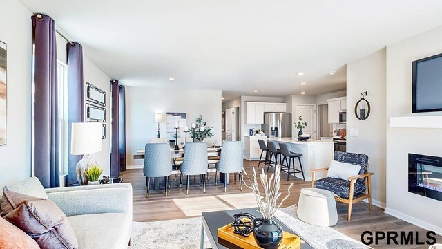 17650 Portal St, Omaha, NE 68136 - living room with a glass covered fireplace, baseboards, light wood finished floors, and recessed lighting
