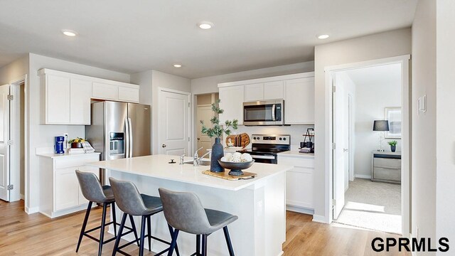 17650 Portal St, Omaha, NE 68136 - kitchen featuring a center island with sink, white cabinetry, a kitchen breakfast bar, and appliances with stainless steel finishes