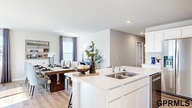 17650 Portal St, Omaha, NE 68136 - kitchen with an island with sink, light countertops, a sink, light wood finished floors, and stainless steel appliances