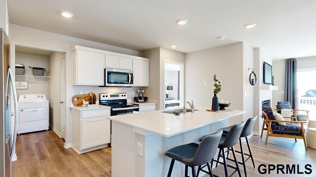 17650 Portal St, Omaha, NE 68136 - kitchen featuring a kitchen breakfast bar, washer / clothes dryer, a sink, light wood finished floors, and appliances with stainless steel finishes