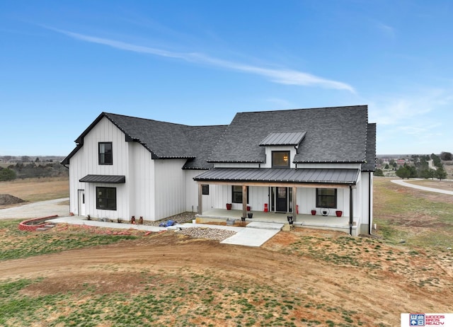 modern farmhouse style home featuring covered porch, metal roof, board and batten siding, and roof with shingles