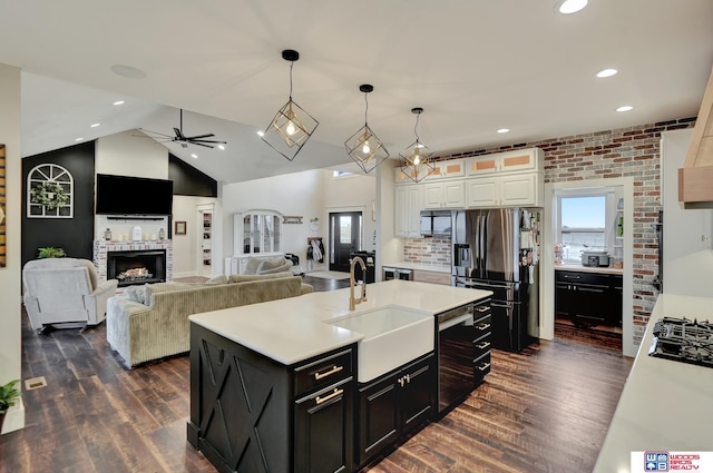 kitchen with ceiling fan, a fireplace, white cabinetry, a sink, and fridge with ice dispenser