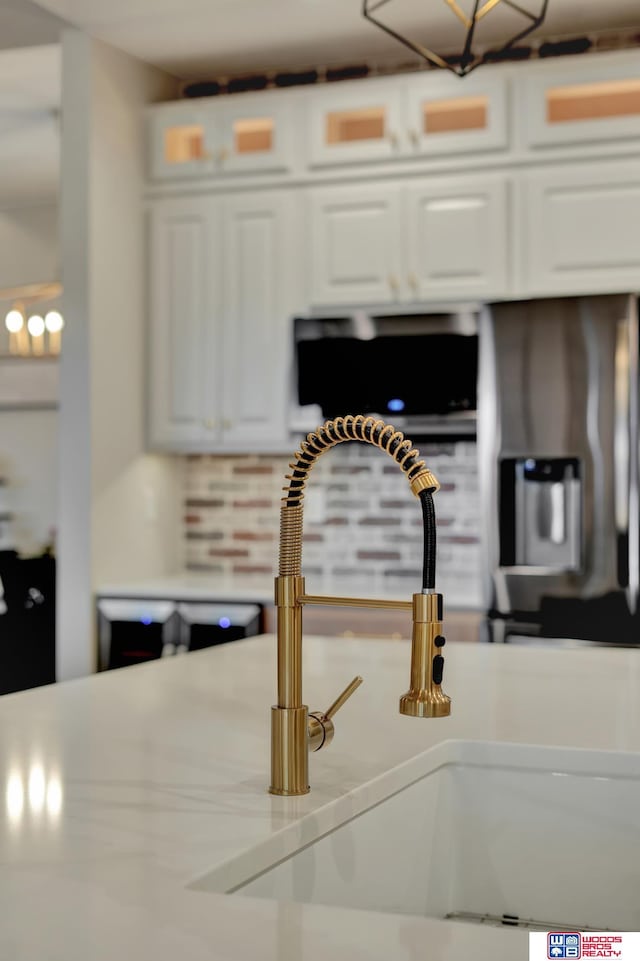 interior details with glass insert cabinets, white cabinets, light countertops, and a sink