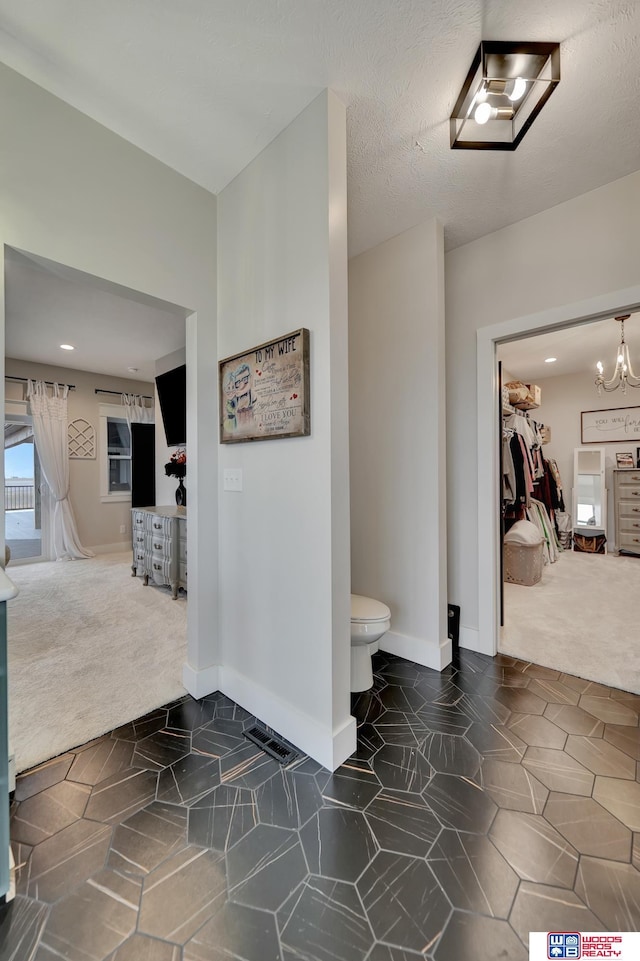 bathroom featuring toilet, a notable chandelier, baseboards, and a textured ceiling
