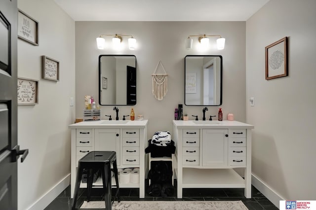 bathroom featuring baseboards, a sink, and two vanities