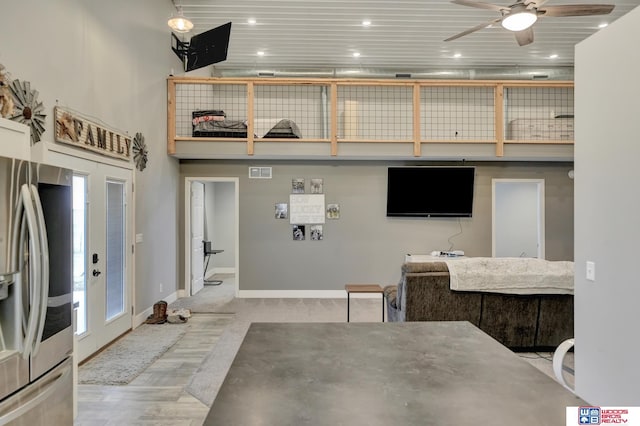 interior space featuring visible vents, baseboards, wood finished floors, a ceiling fan, and a high ceiling