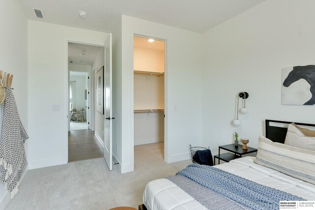 carpeted bedroom with baseboards, visible vents, a closet, and a walk in closet