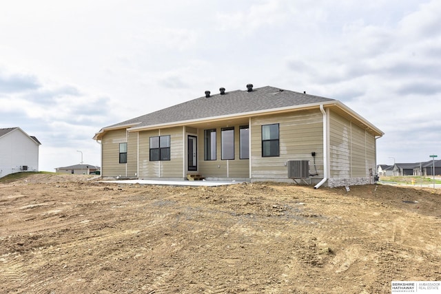 rear view of property featuring central air condition unit and roof with shingles