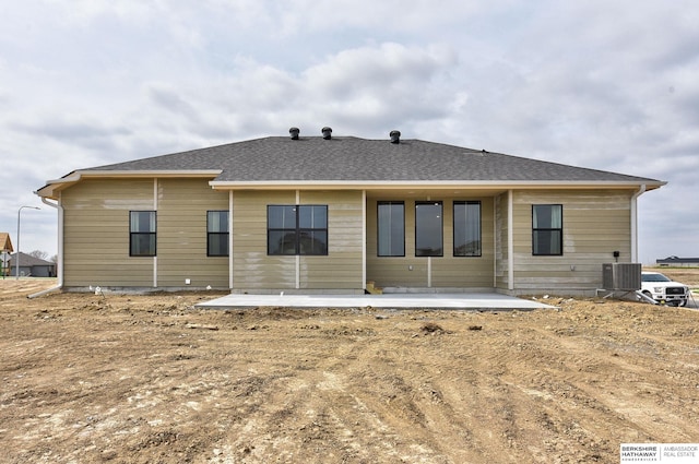 back of property featuring central air condition unit, roof with shingles, and a patio