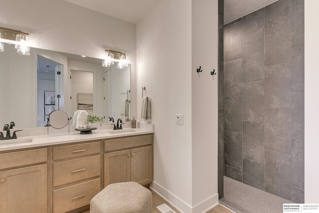 bathroom with walk in shower, double vanity, baseboards, and a sink