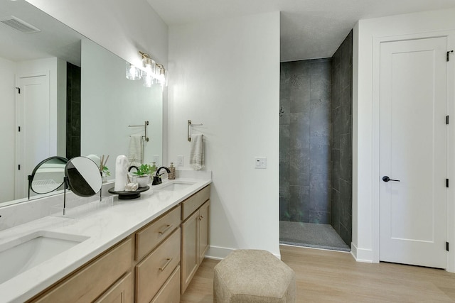 bathroom with walk in shower, wood finished floors, visible vents, and a sink