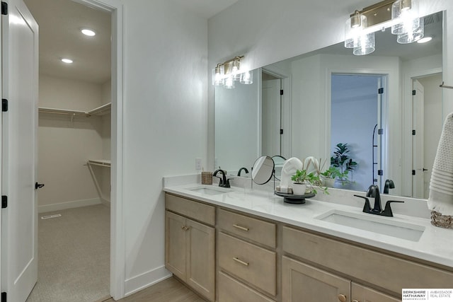 full bathroom featuring a spacious closet, baseboards, a sink, and double vanity