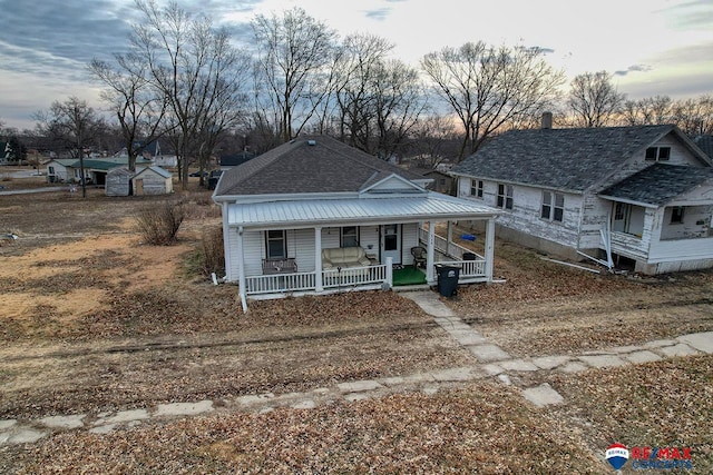view of front of house with driveway, covered porch, and roof with shingles