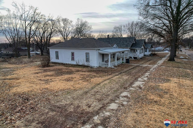 back of property with covered porch and a shingled roof