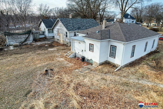 exterior space featuring a shingled roof and a chimney