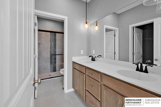bathroom featuring a stall shower, double vanity, toilet, and a sink