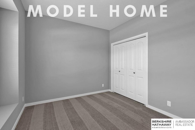 unfurnished bedroom with carpet flooring, a closet, baseboards, and vaulted ceiling