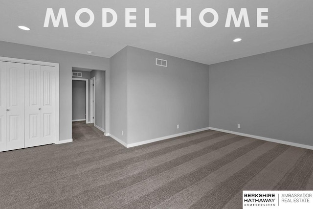 interior space featuring baseboards, visible vents, and dark carpet