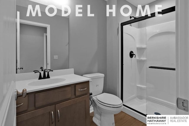 bathroom featuring a stall shower, wood finished floors, toilet, and vanity
