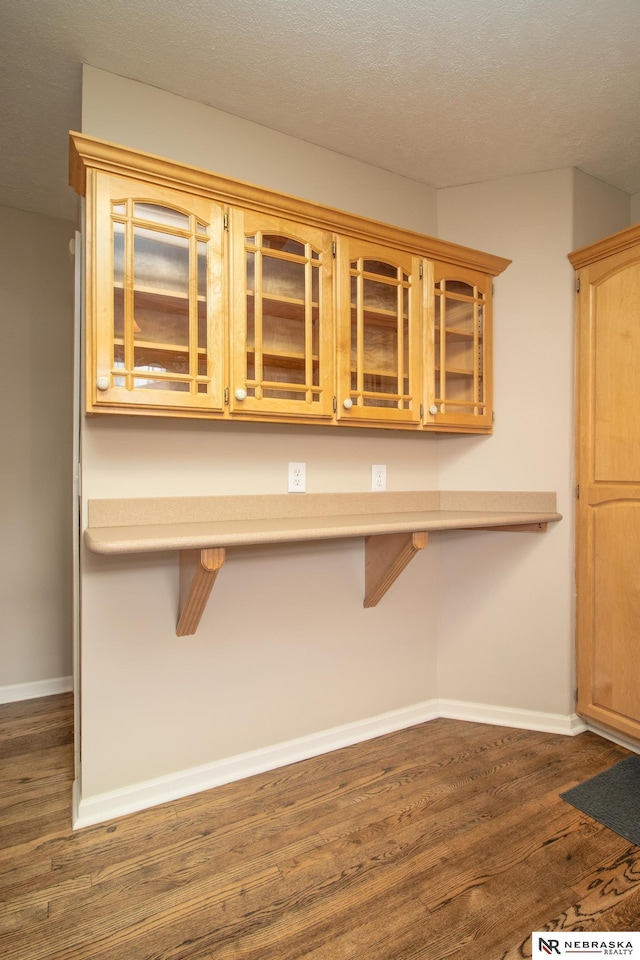 1465 Grant St, Blair, NE 68008 - kitchen with dark wood-style floors, glass insert cabinets, baseboards, and a kitchen breakfast bar