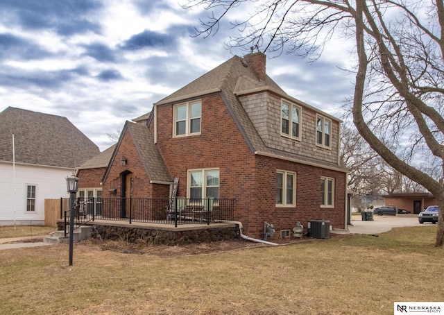 1465 Grant St, Blair, NE 68008 - back of property with roof with shingles, a wooden deck, central AC unit, brick siding, and a lawn