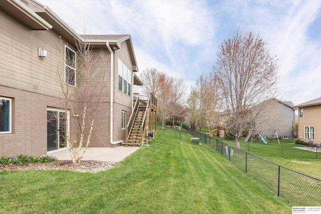 view of yard featuring stairway, fence, a patio area, and a playground