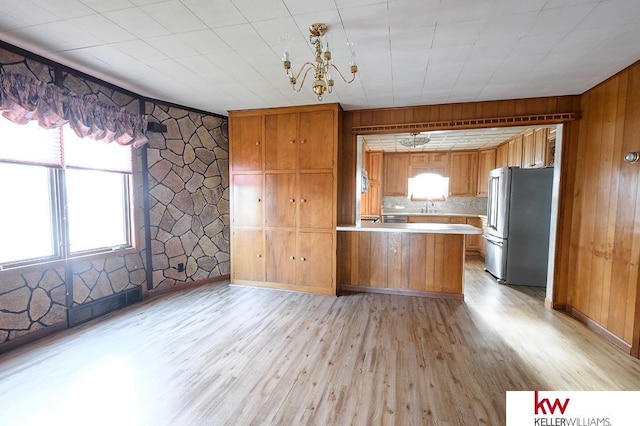 kitchen with brown cabinets, a sink, light countertops, light wood-style flooring, and freestanding refrigerator