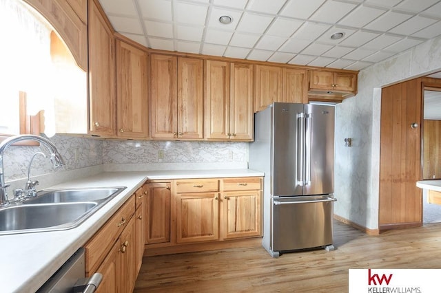 kitchen featuring light countertops, stainless steel appliances, a sink, and light wood-style floors
