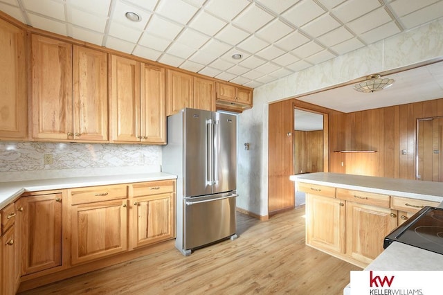 kitchen featuring light countertops, high end fridge, black electric range oven, and light wood-style floors