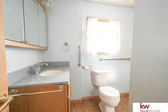 half bathroom featuring vanity, baseboards, toilet, and wood finished floors