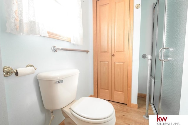bathroom featuring toilet, wood finished floors, and a stall shower