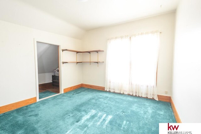 unfurnished bedroom with carpet floors, baseboards, and vaulted ceiling