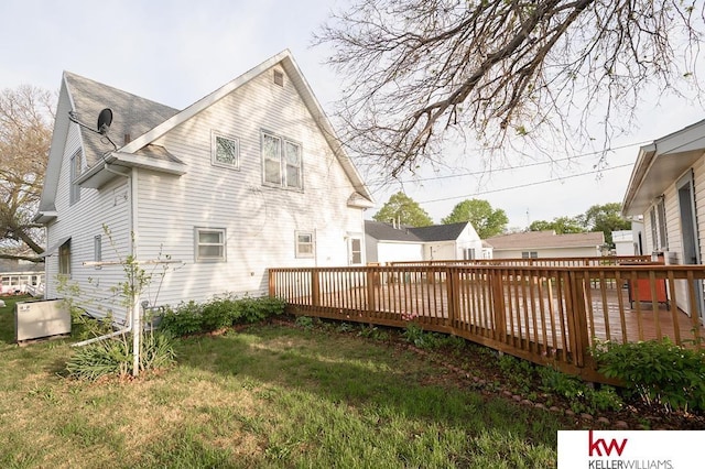 rear view of house featuring a lawn, a wooden deck, and a shingled roof
