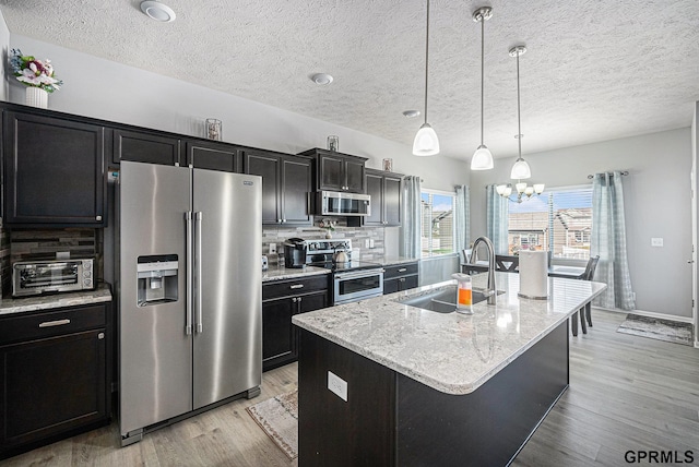 16604 Weber St, Bennington, NE 68007 - kitchen with an island with sink, a sink, tasteful backsplash, dark cabinetry, and appliances with stainless steel finishes