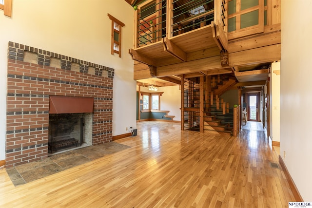 unfurnished living room featuring a healthy amount of sunlight, baseboards, wood-type flooring, and stairs