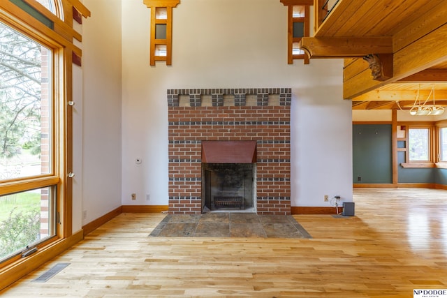unfurnished living room featuring visible vents, baseboards, wood finished floors, and a fireplace