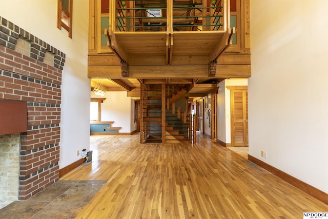 unfurnished living room with baseboards, wood finished floors, stairway, and beam ceiling