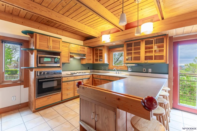 kitchen with black oven, beam ceiling, light tile patterned flooring, wood ceiling, and stainless steel microwave