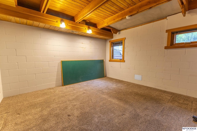 empty room with concrete block wall, carpet flooring, wooden ceiling, and beamed ceiling